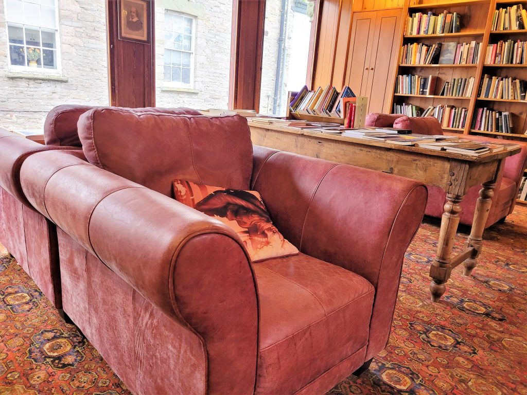 Some armchairs and a table in a cosy looking corner. With lots of books.